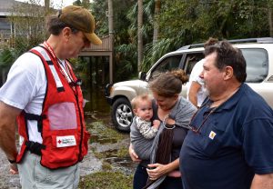 Folly Beach resident Edward Oswald, right, with his daughter Amanda and 8-month old granddaughter Sydney share impressions of the aftermath of Hurricane Matthew with Red Cross volunteer Bailey Williams. They were thankful that there was only minor damage to Edward’s home. Photo Credit: Bob Wallace/American Red Cross.
