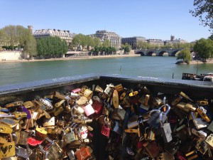 Lovers fasten locks to a pedestrian bridge over the River Seine.  The practice has gotten to be a weighty nuisance for local authorities.  