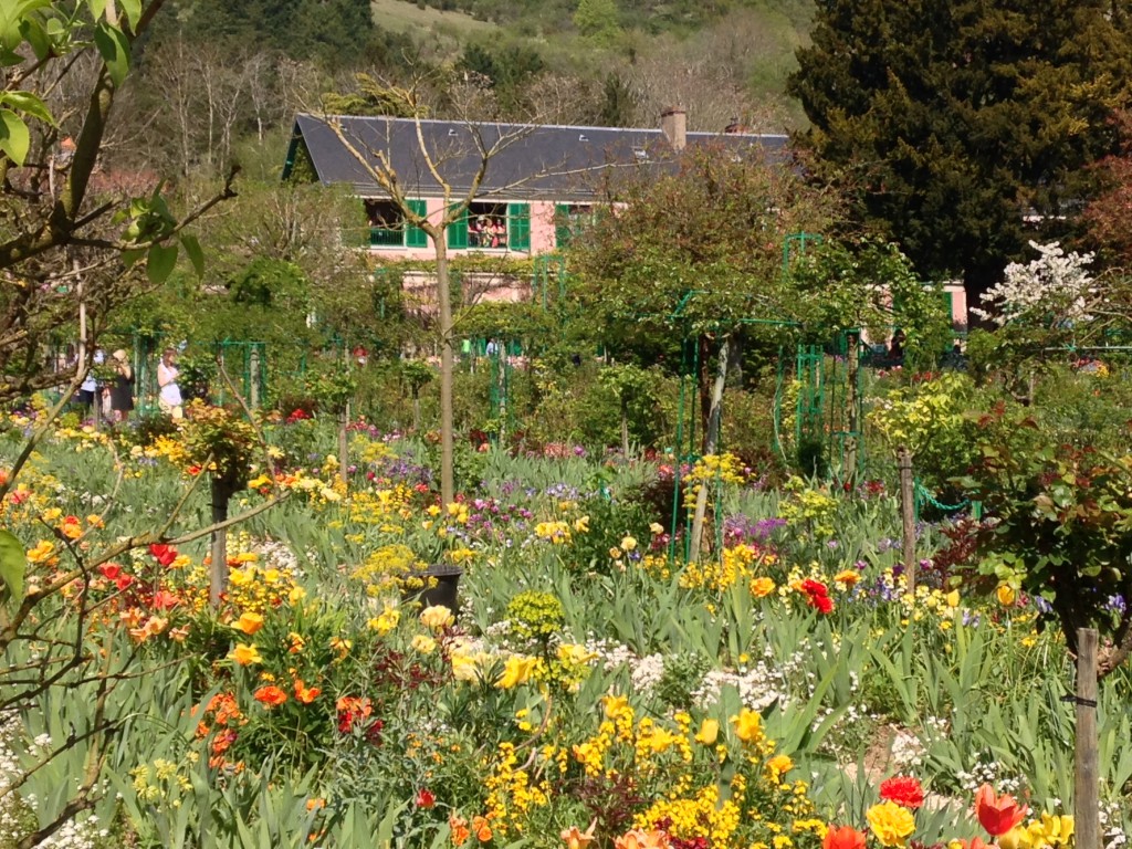 You can see open windows of the second floor of Monet's country home through the tangle of flowers in bloom.