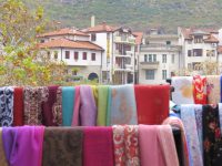 Scarves on sale at a Market in Mostar with the town pictured in the background. (Michael Kaynard)